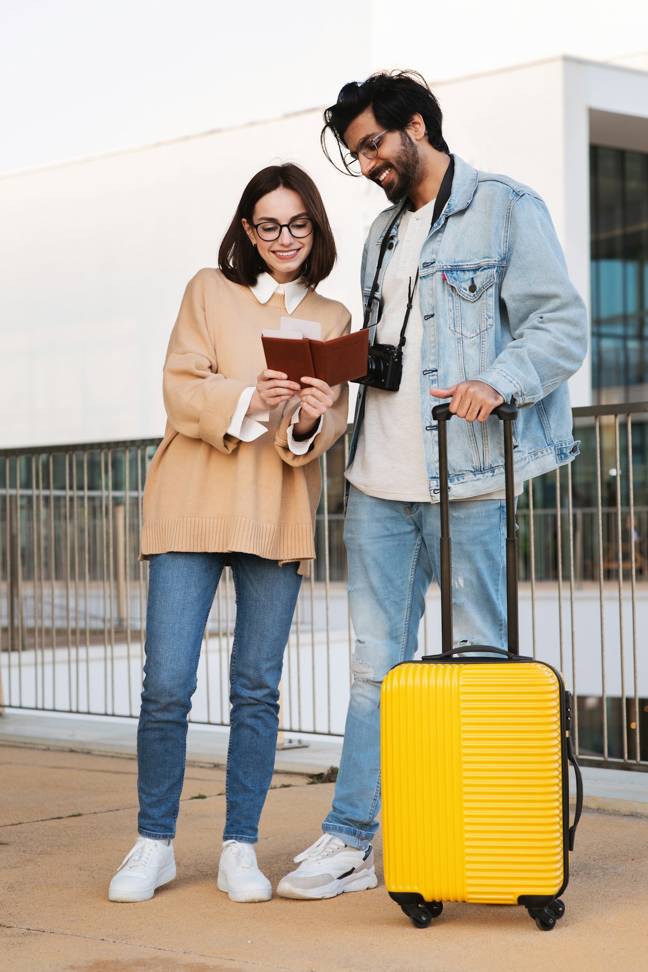 Glad millennial multiethnic family tourists with yellow suitcase look at passport, enjoy trip in