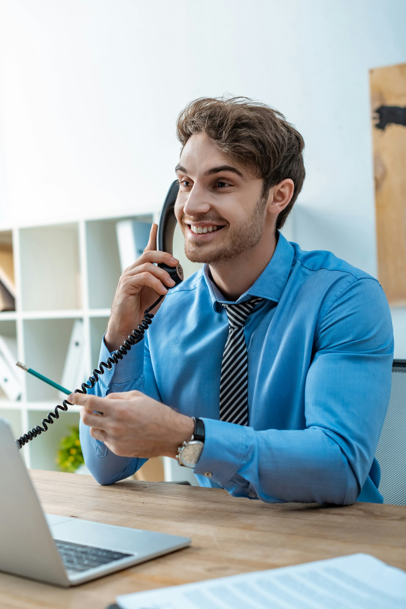 cheerful travel agent talking on phone while holding pencil
