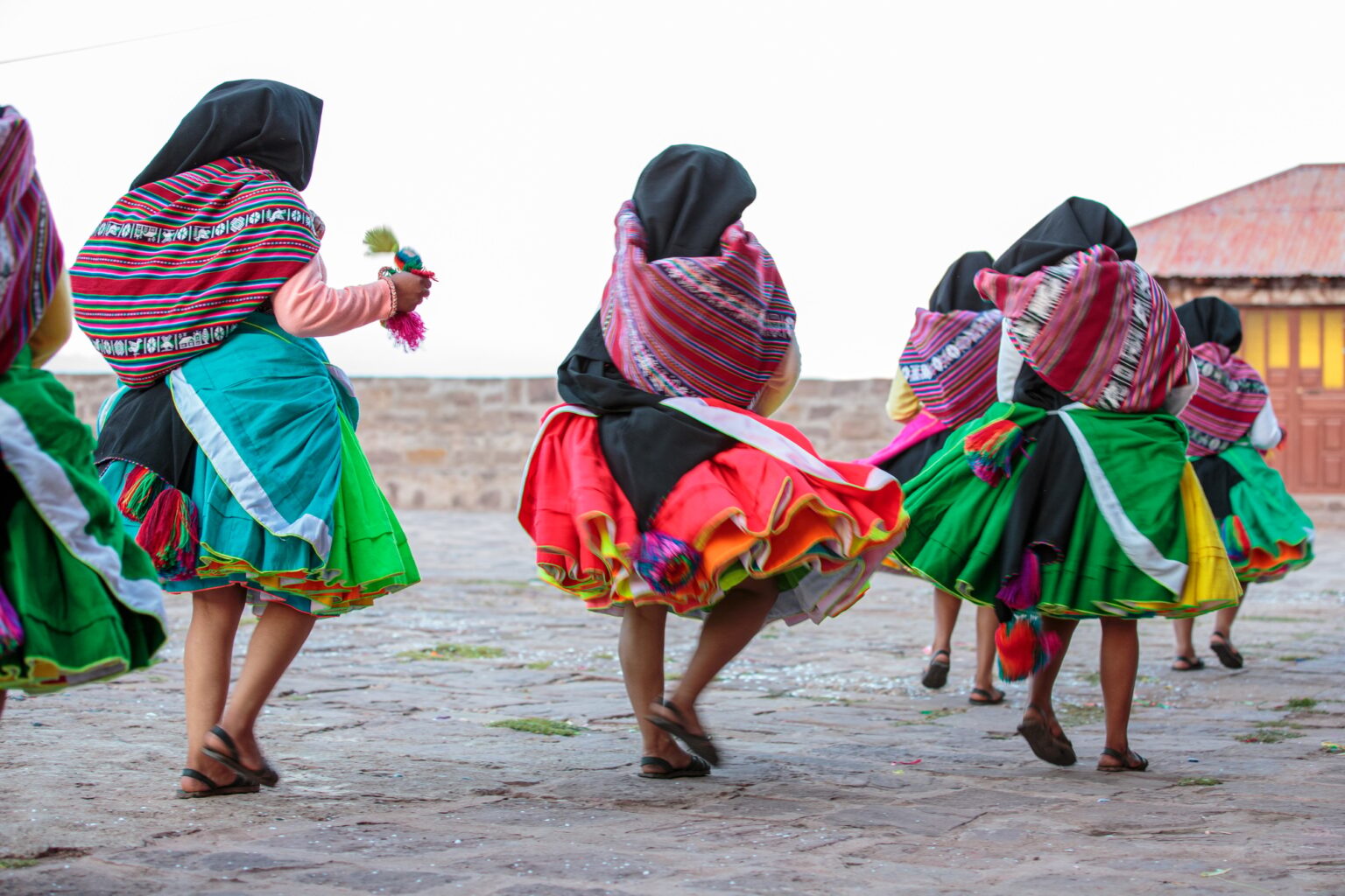 Group of unrecognizable Peruvian women dancing in the town square in traditional dress on Taquile Is